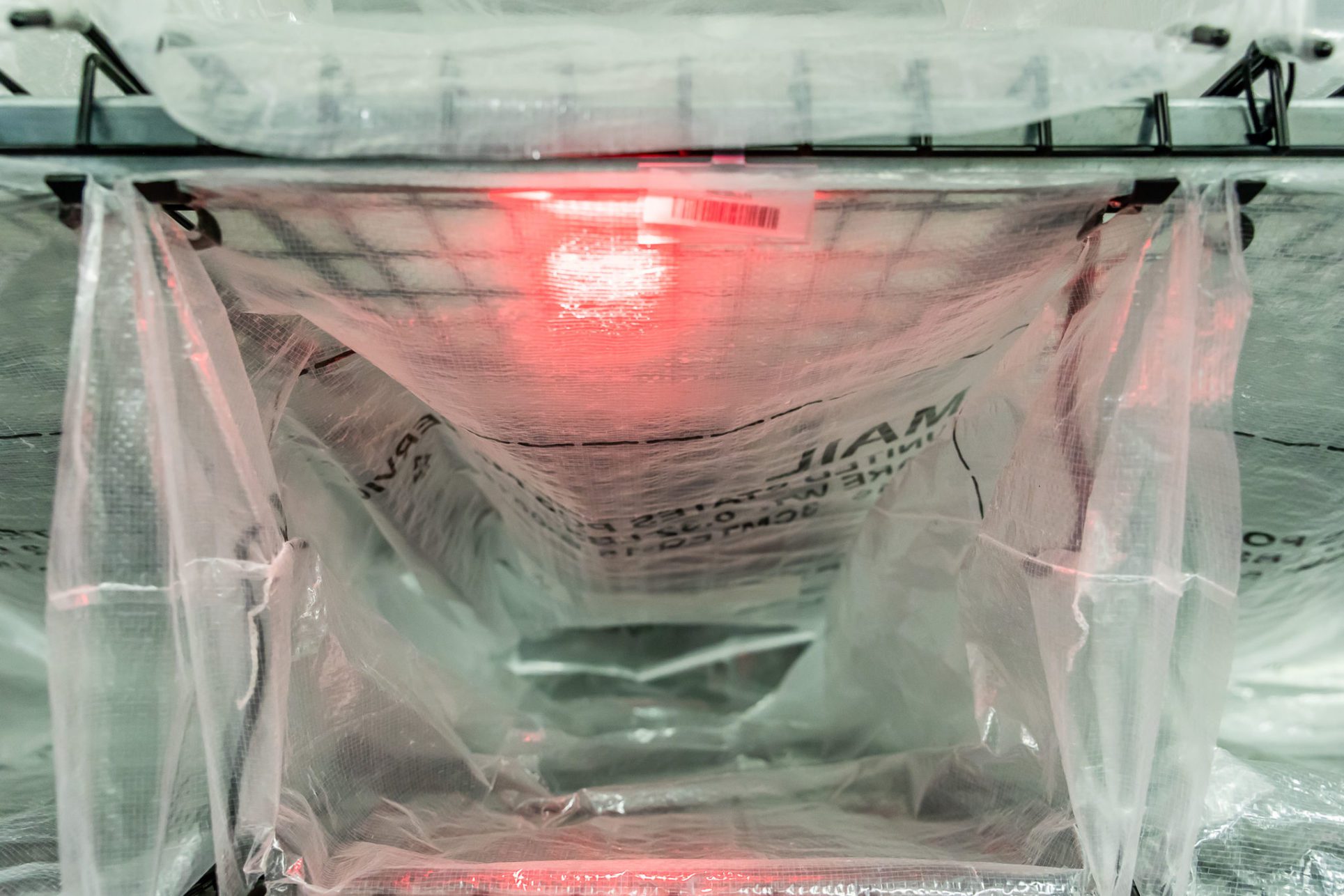A U.S.P.S. mail bag attached to Engineering Innovation's LightSort Sort-to-Light bag rack is lit up with a red L.E.D.