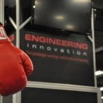 Close-up photo of red boxing gloves that say "The Champ" in focus, unfocused background with Engineering Innovation logo.