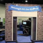 Large arch made to look like an warehouse garage door and brick wall leading into Engineering Innovation's booth for the 2014 Modex trade show.