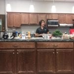 Dietitians standing behind a kitchen counter covered with healthy appetizers.