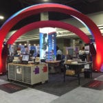 Engineering Innovation's booth with large red arches and several mail sorting machines at the 2016 Modex trade show.