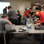 Customer support technicians taking apart computers during a training session at Engineering Innovation.
