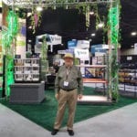 C.O.O. Don Caddy wearing a safari hat while standing at the Engineering Innovation jungle-themed trade show booth