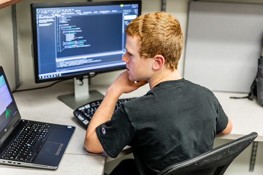 Close-up of Engineering Innovation software team member, Troy Honnegar, coding on at his desk.