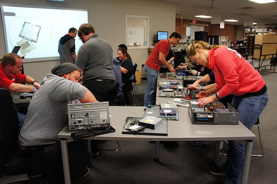 Group of Engineering Innovation customer support technicians taking apart computers.