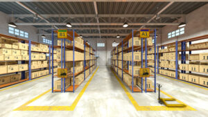 A well-lit warehouse interior with shelves full of stacked cardboard boxes. Two aisles are labeled B1 and A1, and a yellow hand pallet truck is positioned on the right.