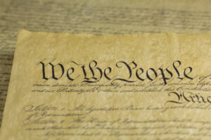 A close-up of the United States Constitution, focusing on the large, ornate text "We the People" written in black ink on aged, yellowed parchment paper.